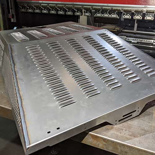 Hands of a man controlling a piece of metal as he bends it using a press brake machine.