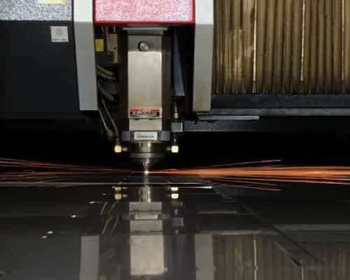 sparks flying as a machine uses laser to cut into a thick piece of metal